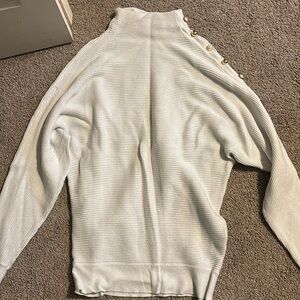 White sweater with bead design on shoulder.